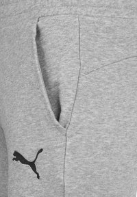 Gray sweatpants featuring a side pocket and a black Puma logo. The fabric is soft with a smooth texture and a classic athletic fit.
