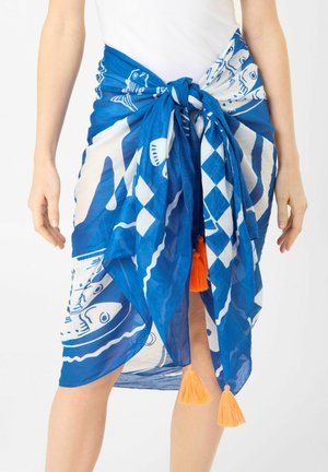 Blau-weiß gemusterter Sarong, in der Taille mit orangefarbenen Quasten gebunden, über weißer Kleidung getragen, zeigt den Bereich von der Mitte des Oberschenkels bis zur Taille.