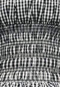 Υφασμάτινο σχέδιο σε ασπρόμαυρο καρό με ραφή με ελαστικό που δημιουργεί οριζόντιες ρυτίδες και υφή.