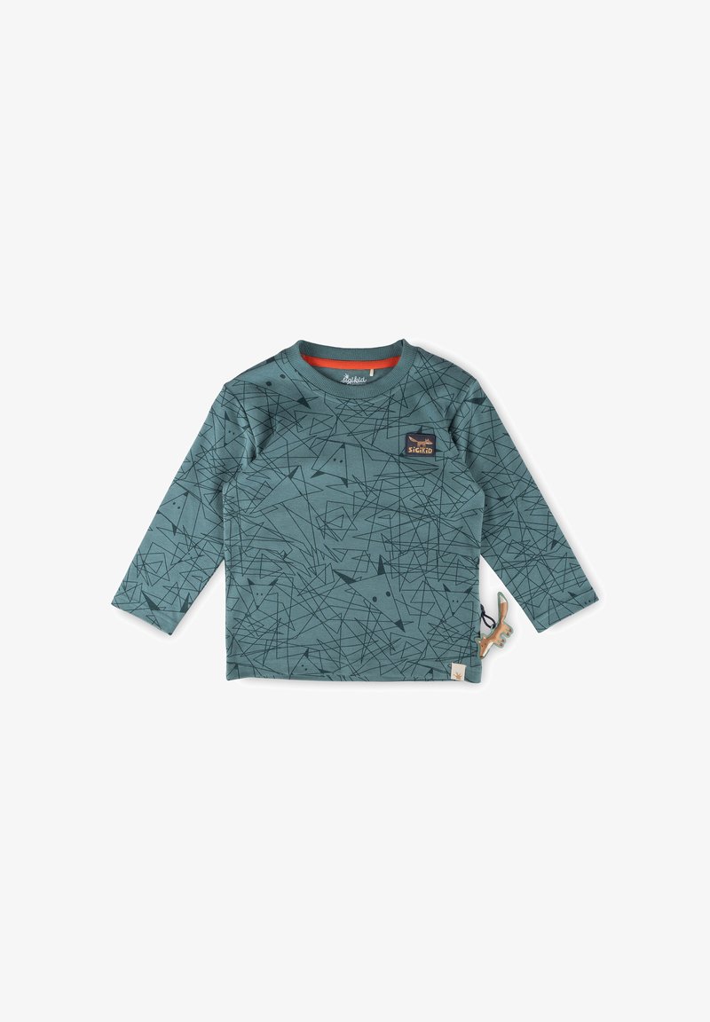 Grünes Langarmshirt mit geometrischen schwarzen Mustern, Rundhalsausschnitt und kleinem braunen Logo auf der Brust. Enthält ein Stoffetikett und ein tierisches Accessoire.