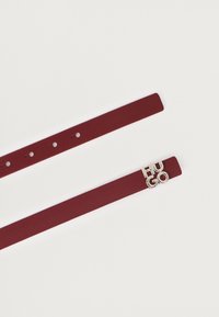 Bracelet en cuir bordeaux avec le logo "HUGO" en silver, comportant cinq trous pour un ajustement et une texture lisse. Design simple et Minimaliste.