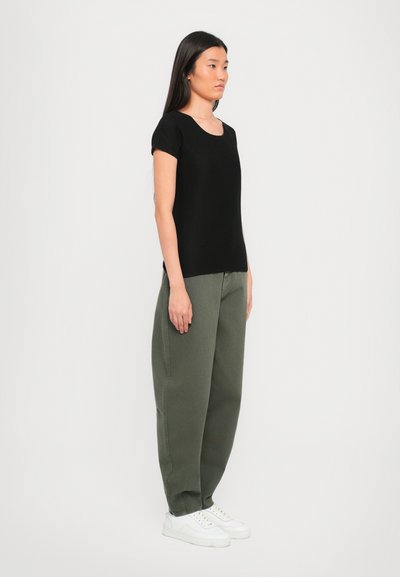Black short-sleeve top with a round neckline, paired with olive green baggy pants and white sneakers, featuring a relaxed fit.