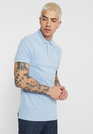 Light blue polo shirt with a textured fabric, white trim on the collar and sleeves, featuring a small embroidered logo on the chest.