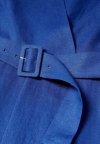 Ceinture en tissu bleu avec une boucle rectangulaire recouverte, fixée à travers un trou, sur un fond textile bleu assorti.