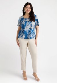 Blue floral print top with square neckline, short sleeves, paired with beige tapered pants and strappy white heels.
