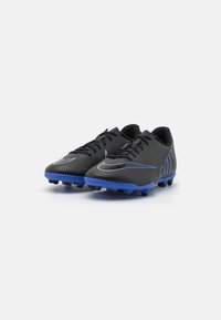 Botas de fútbol negras con rayas texturizadas, con acentos azules en la suela y un logo plateado en el costado. Diseñadas para el rendimiento.