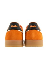 Baskets basses en daim orange avec des accents noirs, présentant un contrefort texturé et une semelle en gomme. Logo sur le talon en orange.