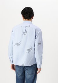 Light blue button-up shirt with black insect pattern, featuring long sleeves and a back pleat for added shape.