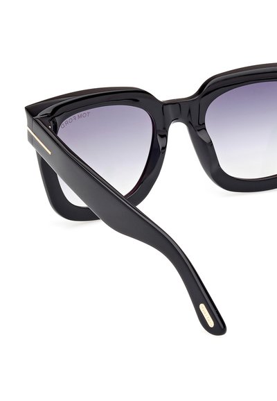 Zwarte oversized cat-eye zonnebril met gradient lenzen, glanzende afwerking en slanke gouden accent op de arm. Soepele textuur en gedurfde vorm.