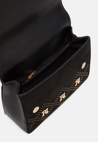 Czarna torebka zamszowa z gładkim wykończeniem ze skóry, wyposażona w złote okucia, detale z ćwiekami w kształcie zygzaka oraz wewnętrzną kieszeń na zamek.