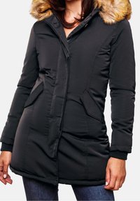 Černá péřová bunda s kožešinou na kapuci, zipovým zapínáním a bočními kapsami. Má žebrované manžety a mírně delší lem. Matný povrch.