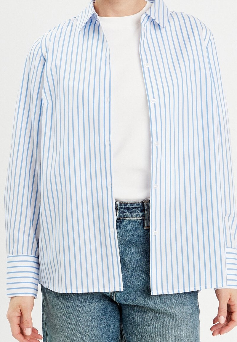 Lichtblauw en wit gestreept overhemd met knoopsluiting aan de voorkant, kraag en lange mouwen. Heeft een ontspannen pasvorm en een zachte, gladde stof.