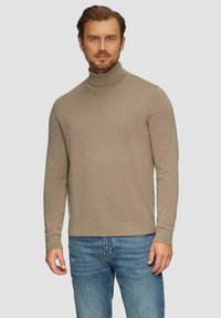 Beżowy sweter z golfem, wykonany z miękkiego, dzianinowego materiału, z długimi rękawami i ściągaczami. Połączony z jasnoniebieskimi dżinsami. Prosty, czysty design.