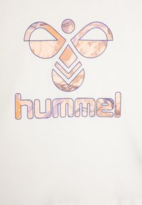 Hvit t-skjorte med et stilisert logo av "hummel" i lilla og pastell marmorert mønster, med geometriske former og jevn tekstur.