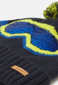 Berretto invernale lavorato a maglia di colore blu scuro, con un design in blu neon e giallo, rifinito con un pompon e un'etichetta in pelle "BARTS" sul bordo.