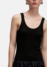 Zwarte geribbelde tanktop met brede schouderbanden en een klassieke ronde halslijn, met een soepele textuur en een aangesloten silhouet.