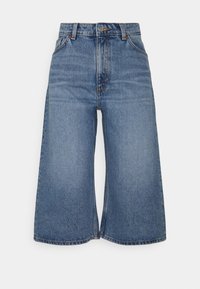 Culottes en denim bleu clair avec une taille haute, dotées d'une fermeture à boutons, de passants pour ceinture, et d'une coupe large et courte.