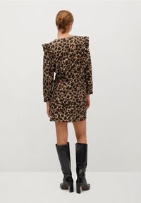 Vestido de estampado de leopardo en marrón y beige con hombros con volantes, de longitud corta y con una silueta ajustada; combinado con botas negras de charol con estampado de cocodrilo hasta la rodilla.