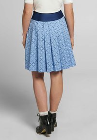 Hellblauer, plissierter Rock mit einem dunkelblauen Elastikbund, der ein weißes Blumenmuster aufweist. Der Stoff wirkt glatt und leicht.