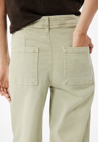 Vaaleanvihreät leveälahkeiset housut, valmistettu puuvillasta. Ominaisuuksiin kuuluu kaksi takataskua ja korkea vyötärö. Suora pinta, jossa on hienovaraisia ommelyksityiskohtia.