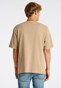 Vaaleanbeige lyhythihainen t-paita rentoa istuvuutta. Kangas on sileä, suora leikkaus ja merkittävät ompeleet olkasaumoissa.