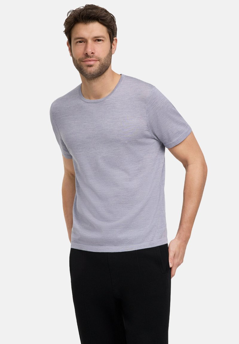 T-shirt grigio chiaro a maniche corte con scollatura rotonda, realizzata in un tessuto morbido, abbinata a pantaloni neri.