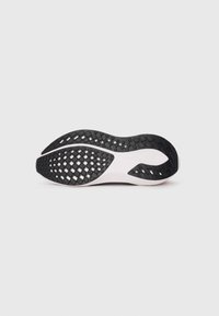 Semelle de chaussure en caoutchouc noir avec un motif texturé et des accents blancs, présentant une forme arrondie et des éléments de traction distincts.