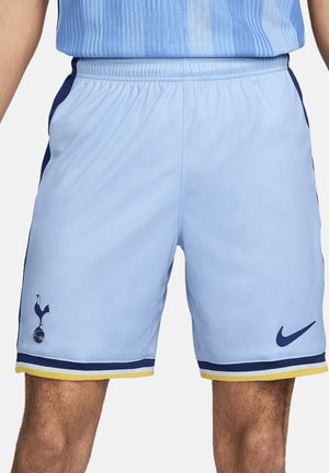 Helle blaue Sportshorts mit marineblauen Akzenten und gelbem Rand, die das Tottenham Hotspur-Logo und einen Nike-Swoosh auf der linken Seite tragen.