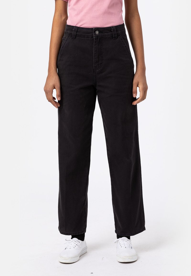 Jean noir à jambes larges avec une taille haute, en coton, doté d'une fermeture classique par boutons à l'avant et d'une texture légèrement délavée.