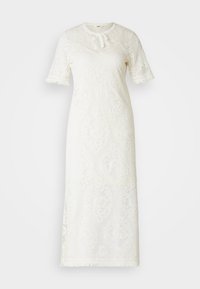 Robe en dentelle blanche avec des manches courtes, un col rond avec un détail à nouer, des motifs élaborés et des accents de franges au niveau de l'ourlet.