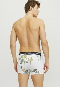 Weiße Boxershorts mit floralem Muster in Grün und Gelb, ausgestattet mit einem schwarzen elastischen Bund mit "JACK & JONES"-Logo.