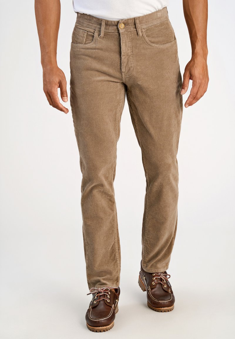 Spodnie kordowe w jasnobrązowym odcieniu, o prostym kroju nogawki, z przednimi kieszeniami i guzikiem, w połączeniu z brązowymi butami typu boat.