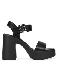 Sandalias de plataforma negras con un tacón grueso, que presentan tiras de cuero suave y un cierre de hebilla metálica. El diseño es minimalista y moderno.