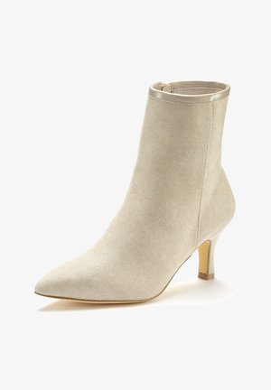 Béžová kotníková bota s texturovaným tkaným povrchem, špičatou špičkou a 5 cm tenkým podpatkem. Má lesklý kovový lem v horní části.