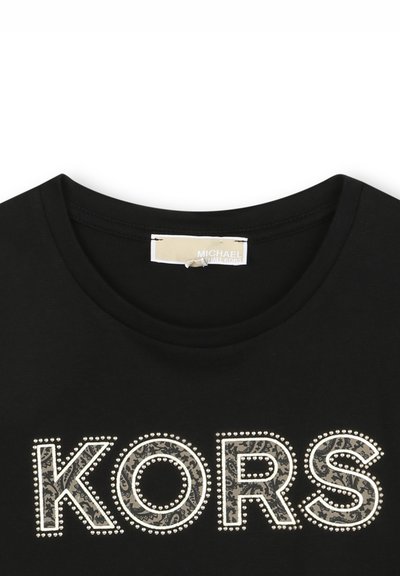 T-shirt en coton noir avec le logo « KORS » imprimé en motif et clous, avec un col rond. Texture lisse et manches courtes.