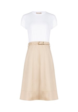 Haut blanc ajusté à manches courtes associé à une jupe beige taille haute en ligne A, avec une ceinture assortie et une boucle dorée.