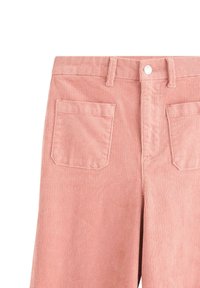 Pink fløjlbukser med lodret ribbet struktur, der har en knaplukning og to baglommer.