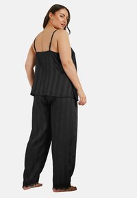 Svart satin pyjamas-set med vertikala ränder, med en ärmlös topp och lösa byxor med spetsdetaljer i fållarna.