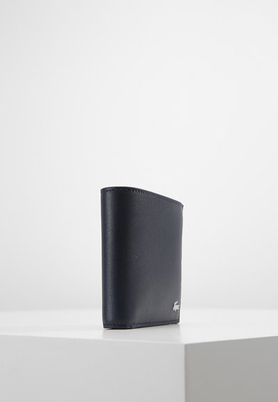 Portefeuille en cuir marine au design épuré et à la texture lisse, arborant un petit logo métallique dans le coin inférieur droit.