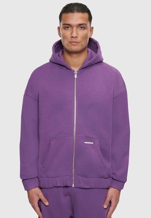 Pull à fermeture éclair violet avec capuche, poches avant, poignets et ourlet côtelés. Fabriqué en tissu doux avec une texture lisse et un minimum de marquage.