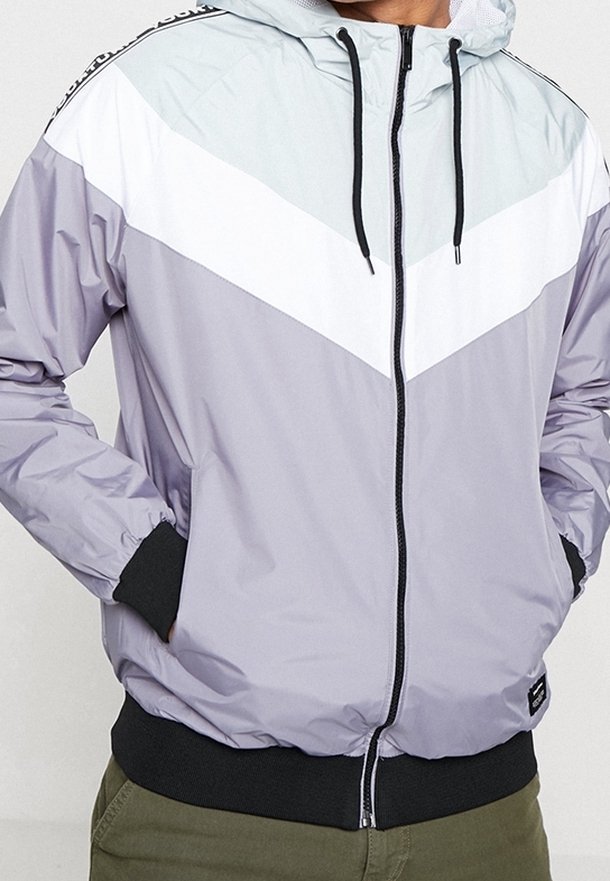 Lättviktsjacka med huva och en chevrondesign i grått, vitt och ljusblått. Inkluderar dragkedjestängning och elastiska muddar.