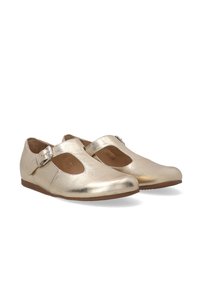 Gouden metalen Mary Jane-stijl schoenen met een uitsnijdontwerp en verstelbare gesp, rustend op een witte achtergrond.