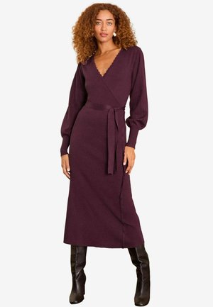 Burgunderfarbene Wickelkleid mit langen Puffärmeln, einem V-Ausschnitt und einem Bindegürtel in der Taille, aus weichem, strukturiertem Stoff. Knielang mit einem seitlichen Schlitz.