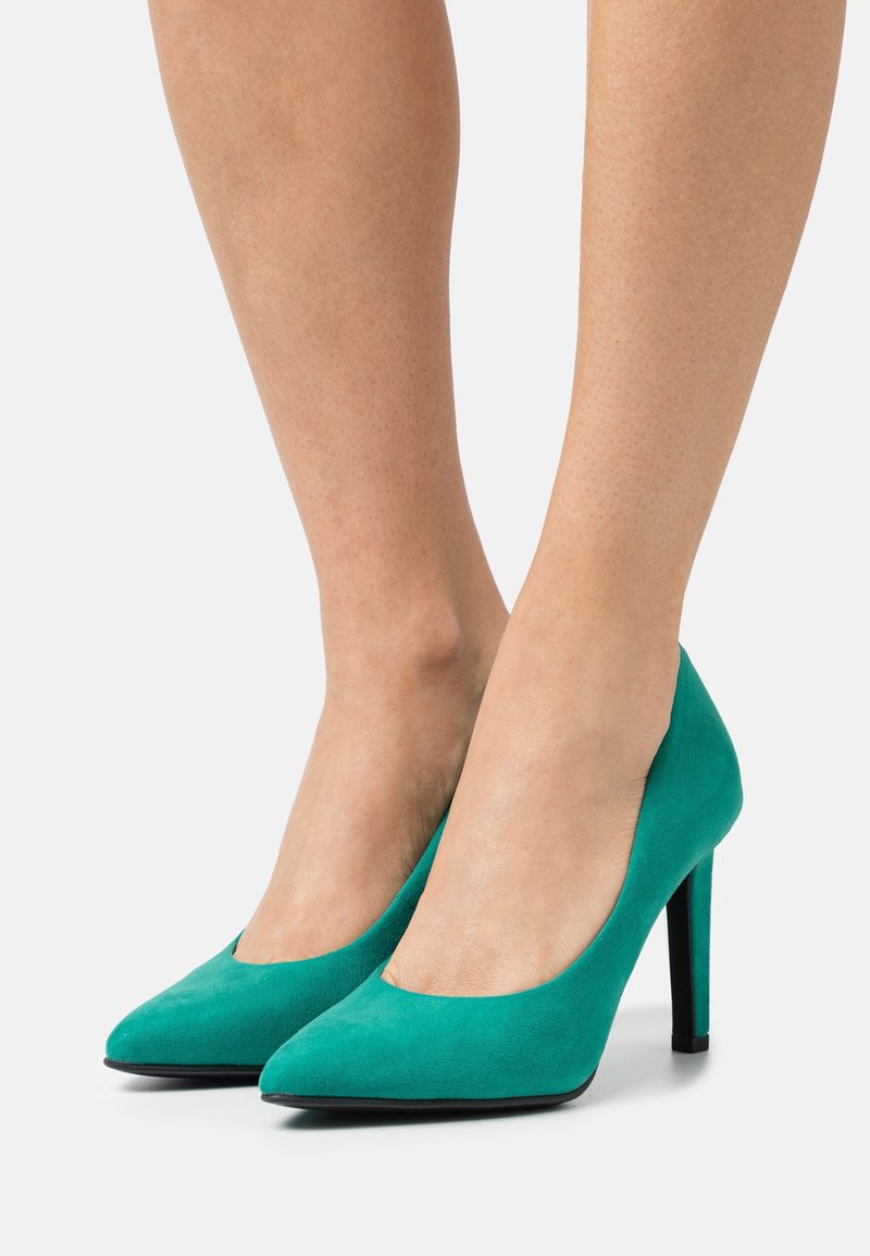 Tacchi alti in suede acquamarina con punta affusolata, texture liscia e un sottile tacco a stiletto nero, caratterizzati da un design con vamp a taglio basso.