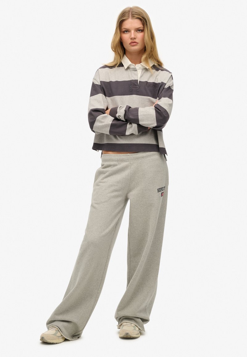 Grijs en donkergrijs gestreepte cropped lange mouwen top met een kraag, gecombineerd met lichtgrijze joggingsbroek met een logo, beide in zachte stof.