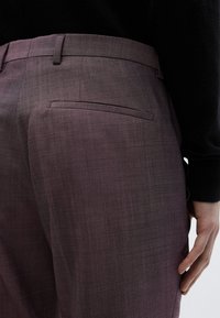 Σκούροι μωβ παντελόνια σε στενή γραμμή με ομαλή υφή, διαθέτουν μια πίσω τσέπη και διακριτικές ραφές.