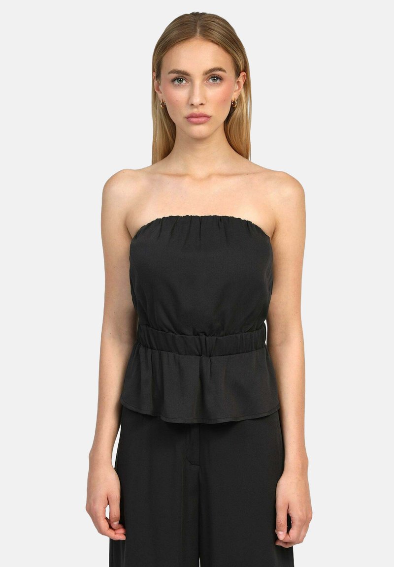Top peplum noir sans bretelles avec taille élastique, présentant une texture lisse et un léger éclat. À associer avec un pantalon noir ample.