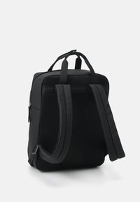 Svart ryggsäck med vadderade axelremmar och ett handtag på toppen, med en slät utsida och en dragkedjefick för förvaring.