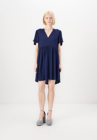 Abito blu navy con scollatura a V e maniche corte a balze, caratterizzato da una vita arricciata e un orlo posteriore leggermente più lungo.