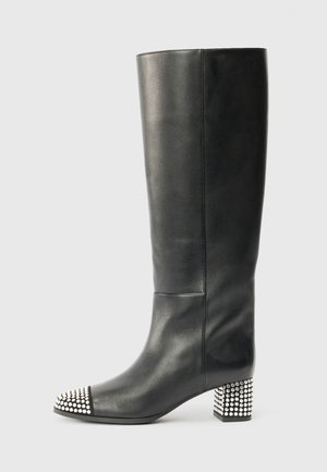 Bottes en cuir noir montantes avec un bout rond, une capuche cloutée en argent et un talon bloc orné de clous pour une texture et des détails.